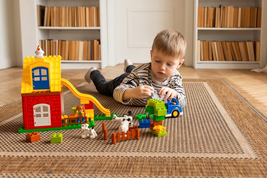 free-photo-of-boy-lying-down-on-carpet-and-playing-with-toys